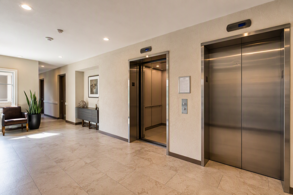 Residential apartment building elevator lobby in Phoenix AZ showing stainless-steel doors and posted inspection certificate for elevator maintenance compliance