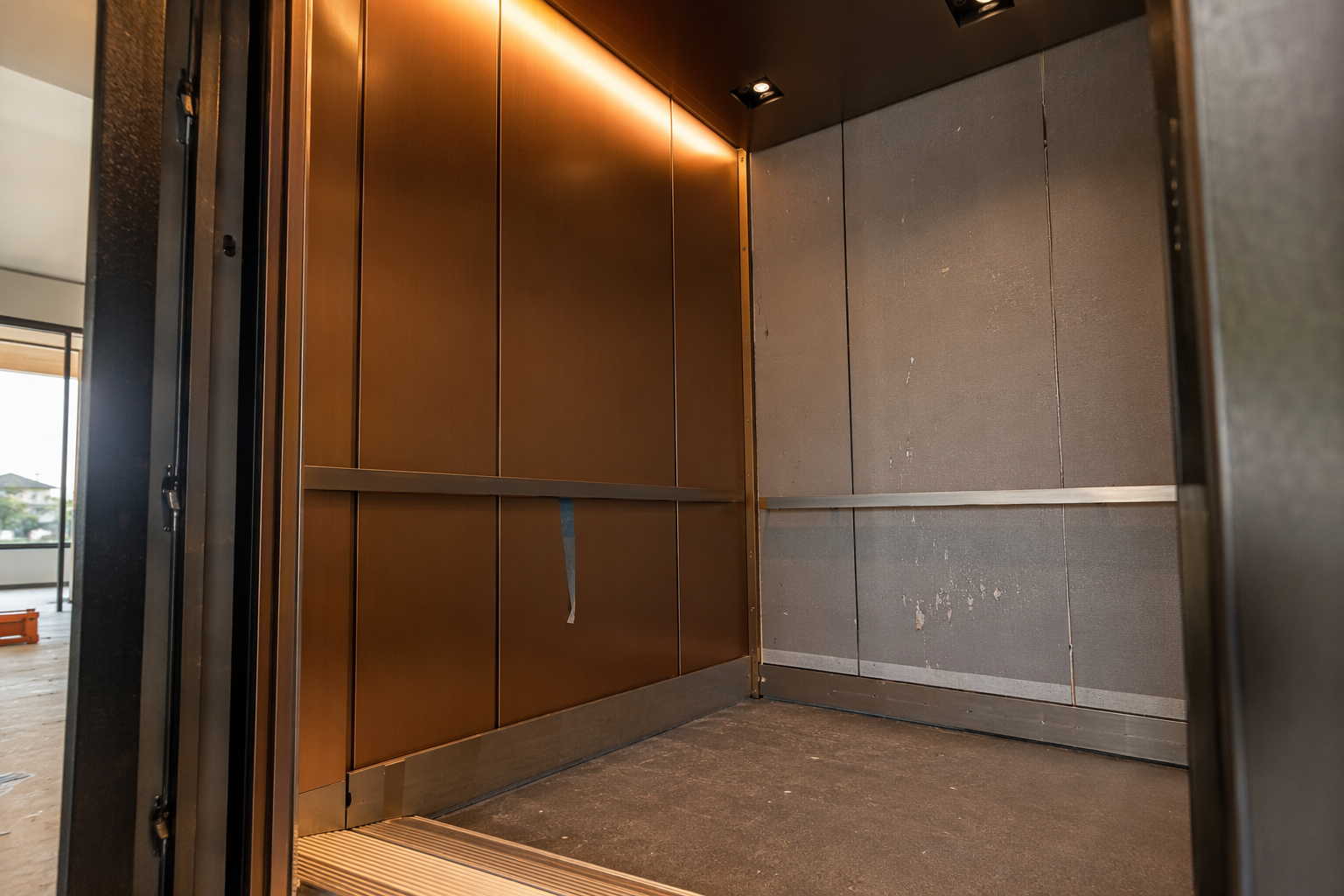 Elevator cab modernization in progress in a Scottsdale Arizona building, showing new bronze wall panels beside existing finishes, subject to ASME A17.1 alteration requirements