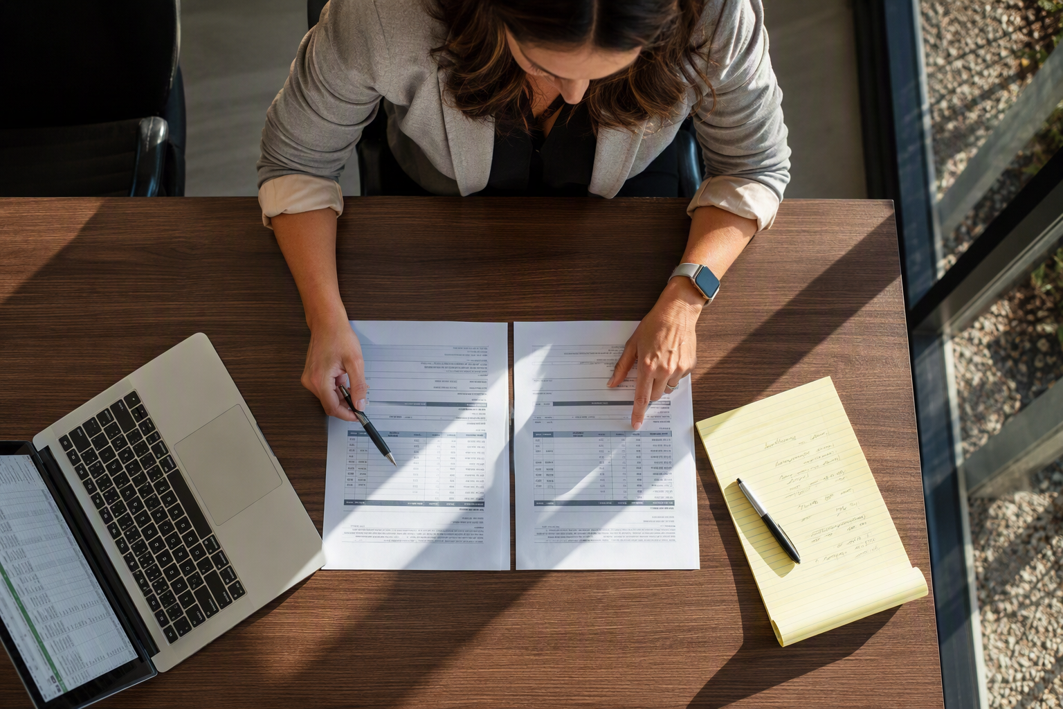 Property manager in a Phoenix AZ office comparing elevator modernization versus full replacement bid documents and cost spreadsheets to determine the best investment decision.