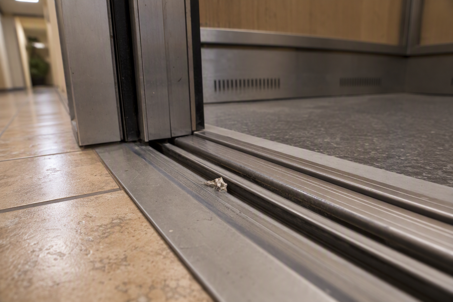 Debris lodged in elevator door sill track causing doors not to close properly, a common elevator problem building staff can check before calling a technician